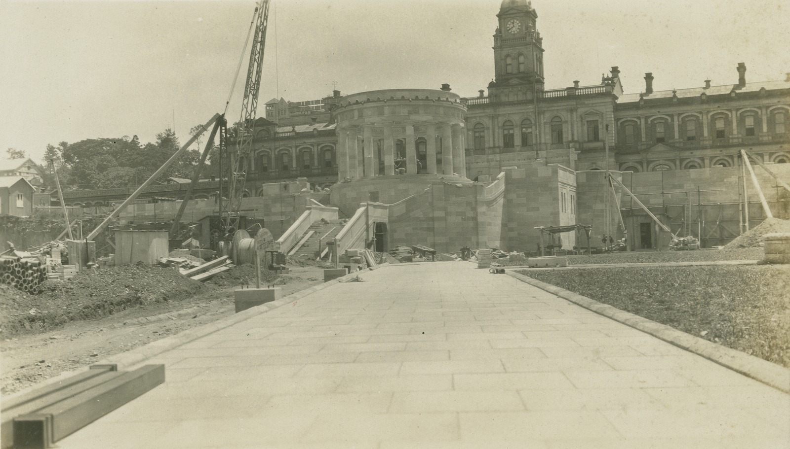 Old photographs of the construction of Anzac Memorial and surrounding square. The Shrine of Remembrance is in the centre with cranes and equipment on the side.