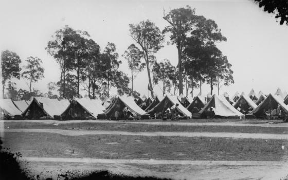 Black and white photograph of tents outside.