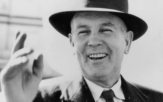 Old photograph of Ben Chifley waving and wearing a hat.