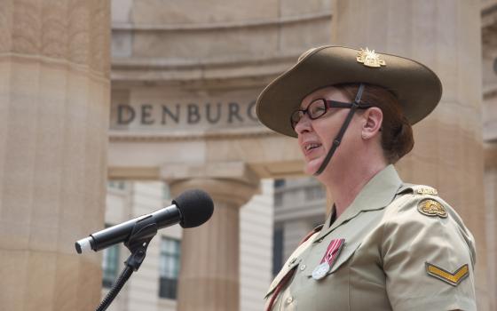Defence force member speaking into a microphone at Anzac Square.