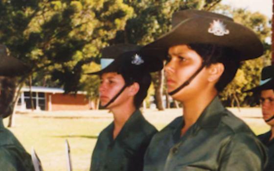 Women standing to attention wearing Australian Army uniform.
