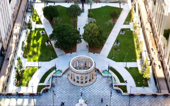 Aerial view of the Anzac Square parklands with the Shrine of Remembrance in the center and tall buildings around the outside.