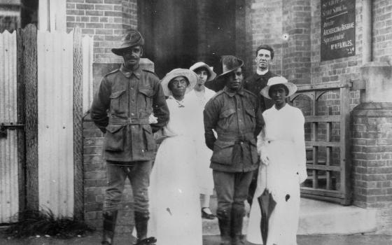 Photographic print of two servicemen stending outside a church with their wives, a bridesmaid and minister.
