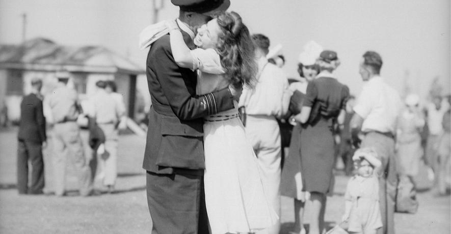 Old photograph of a man and woman embracing. The man is wearing a uniform and the woman is wearing a dress.