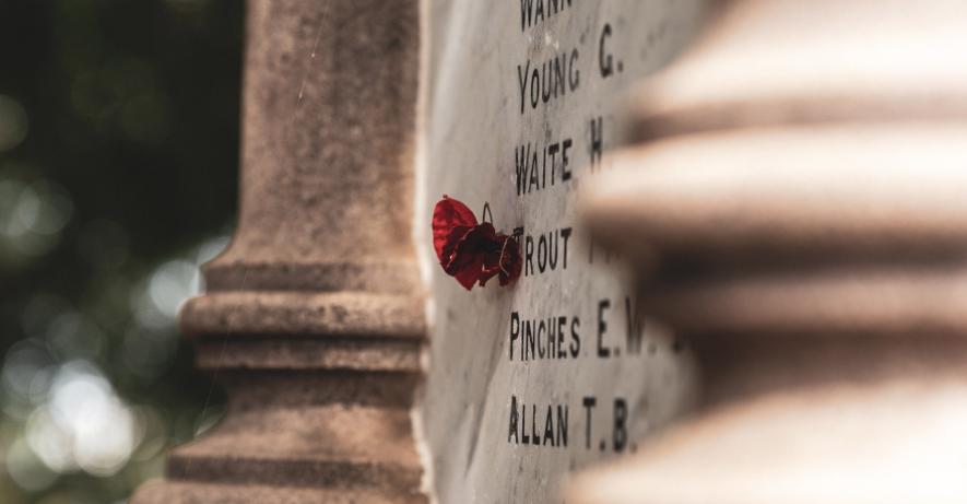 Red poppy attached to a memorial stone. 