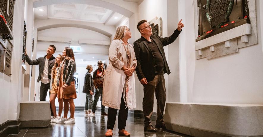 Groups of people walking through the gallery, pointing at plaques on the wall.