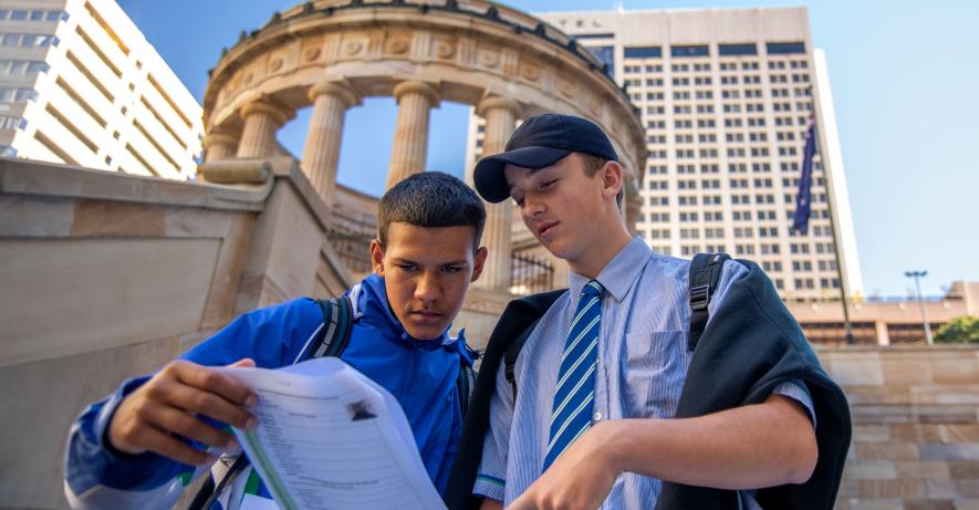 Students holding a worksheet outside Anzac Square with the Shrine of Remembrance in the background.