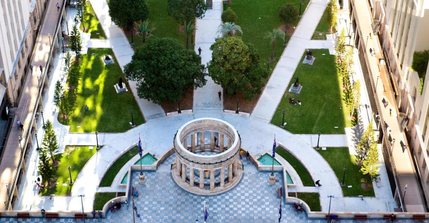 Aerial view of the Anzac Square parklands with the Shrine of Remembrance in the center and tall buildings around the outside.
