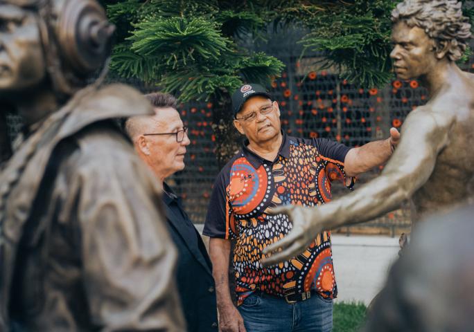 Two men looking at the Aboriginal and Torres Strait Islander Memorial. One man is touching the memorial.